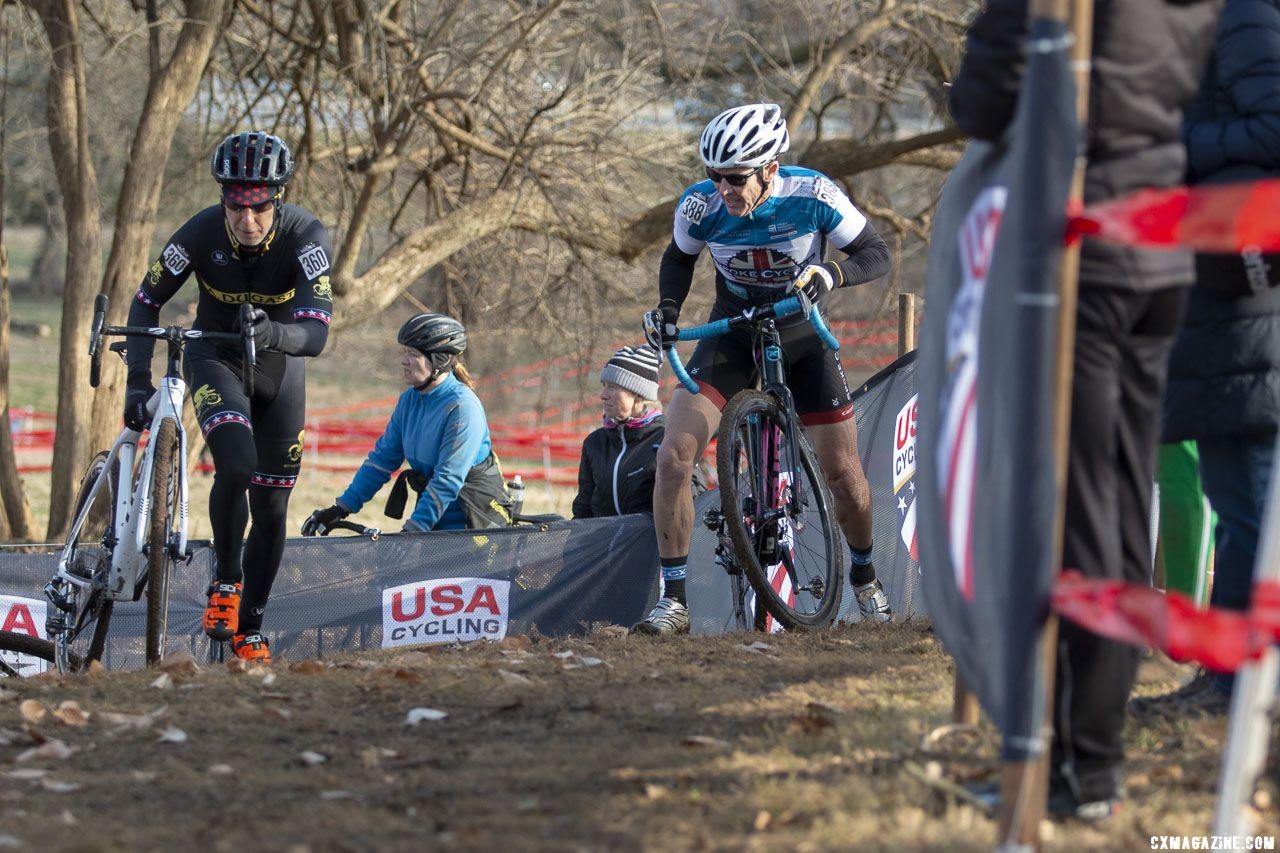 Bob Downs runs while Barney Baxter rides but dabs on lap one. Masters Men 60-64. 2018 Cyclocross National Championships, Louisville, KY. © A. Yee / Cyclocross Magazine