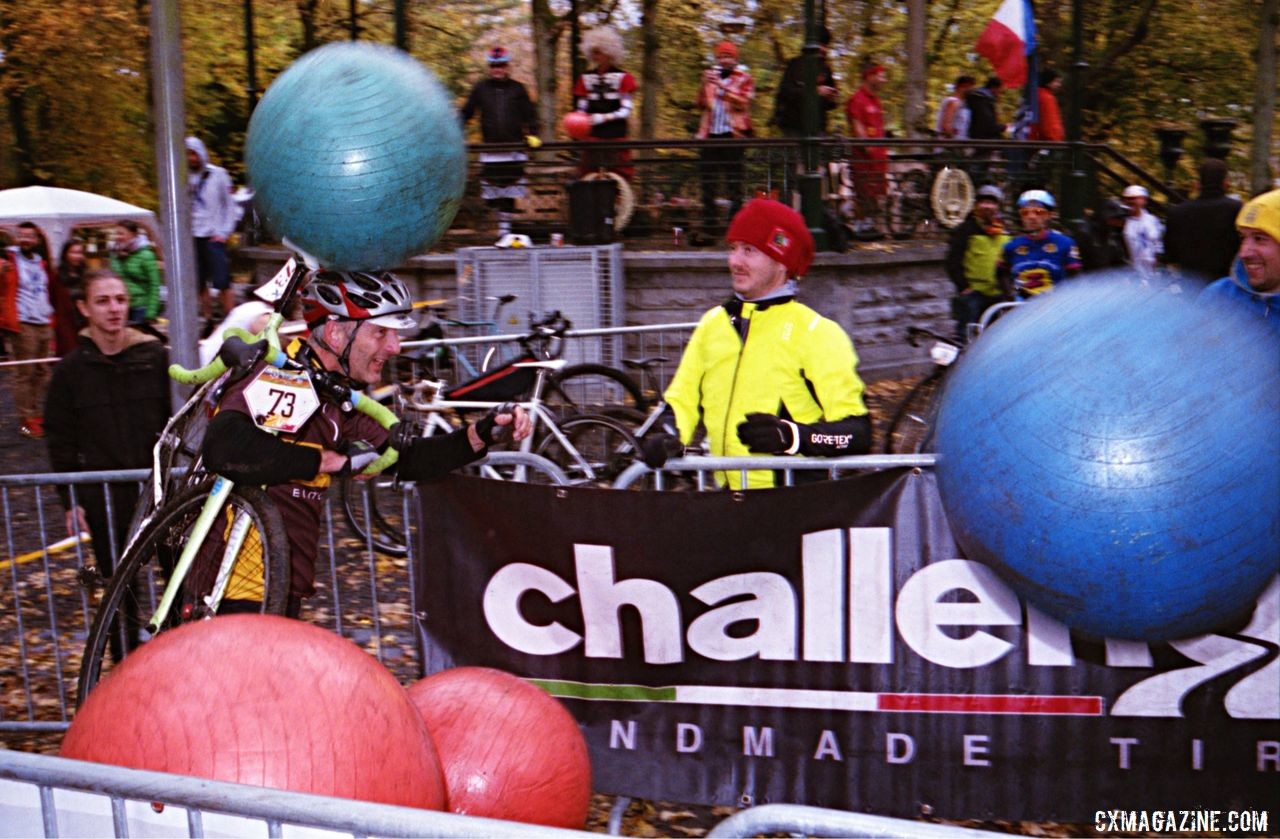 A rider dodges the yoga balls while shouldering his bike. 2018 Single Speed Cyclocross World Championships, Tournai, Belgium. © Anders Bendixen